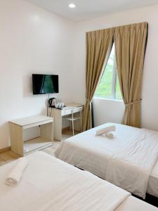 una camera d'albergo con due letti e una finestra di Vvip Hotel a Hutan Melintang