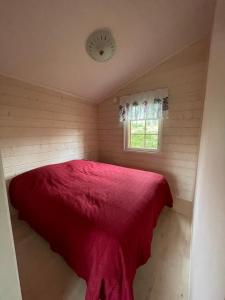 Un dormitorio con una cama roja en una habitación pequeña. en Mökki Ruohola, en Taivalkoski