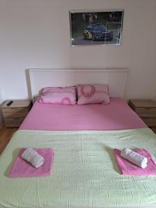 a bed with pink sheets and pink towels on it at Hoste Pikante in Pančevo