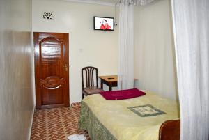 Schlafzimmer mit einem Bett, einem Tisch und einer Tür in der Unterkunft Sundowner Lodge in Nakuru