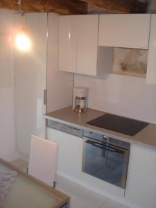 Una cocina con gabinetes blancos y un horno de estufa. en Le pigeonnier, en Virac