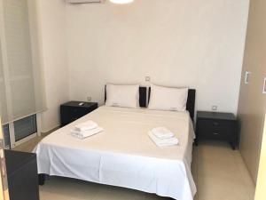 ein Schlafzimmer mit einem weißen Bett mit zwei Handtüchern darauf in der Unterkunft Πολυτελής Βίλα στην άκρη της θάλασσας in Kyllini