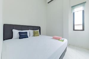 1 cama blanca con almohadas en el dormitorio en Urbanview Hotel La De Grizz Syariah Sampit by RedDoorz, en Sampit