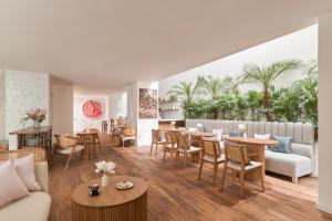 a living room with tables and chairs and palm trees at Silverland Mây Hotel in Ho Chi Minh City