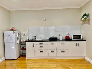 cocina con armarios blancos y nevera blanca en Lifestyle Guesthouse, en Dairy Flat