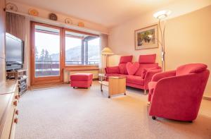 sala de estar con sillas rojas y TV en Rehwiesa Studio C24, en Arosa