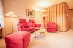un soggiorno con divano rosso e tavolo di Rehwiesa Studio C24 a Arosa