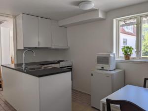 a white kitchen with a sink and a microwave at Casa Bianca in Vadstena