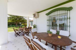 an outdoor patio with wooden tables and chairs at Villa Galemar Pool & Gardens in Torremolinos