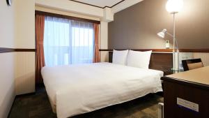 een hotelkamer met een groot bed en een raam bij Toyoko Inn Nishi-kawaguchi-eki in Warabi