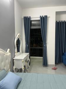 um quarto com cortinas azuis, uma cadeira e uma janela em Tropical Garden em Ấp Long Kiên I