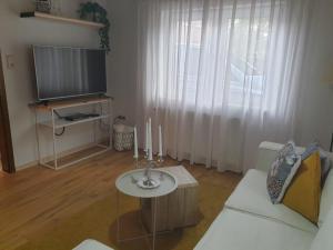 een woonkamer met een witte bank en een televisie bij Kleine Möwe in Dornum