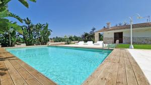 una piscina con terrazza in legno e una casa di Villa Paradiso by Salento Affitti a Marina di Mancaversa