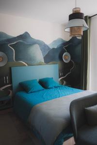 a bedroom with a blue bed with a painting on the wall at Logis de l'Héronière in Salles-sur-Mer