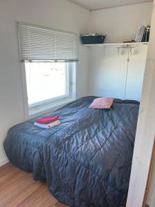 a bedroom with a bed with a blue comforter and a window at Jomsborg Ilulissat in Ilulissat