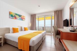 a hotel room with a bed and a desk and a television at AluaSun Helios Beach - All Inclusive in Obzor