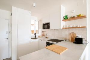 una cucina bianca con mobili bianchi e un lavello di Precioso apartamento en Platja d'Aro, Costa Brava. a Platja  d'Aro