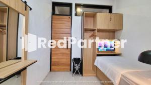 um pequeno quarto com uma cama e uma secretária em Griya Nawastika At Jakal KM 8 Mitra RedDoorz em Kejayan
