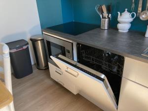 a kitchen with a microwave oven in a counter top at 'Onder-dak' 2-persoons appartement in Zandvoort +2 photos