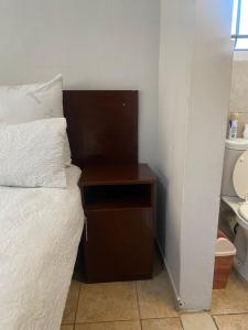 a bedroom with a bed and a nightstand next to a toilet at liam travel inn in Nelspruit