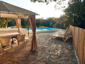 un patio con sombrilla, sillas y piscina en Finca El Palomar, en Fuenteheridos