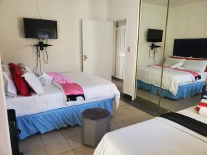 a hotel room with two beds and a mirror at Lancaster Guest House in Boksburg