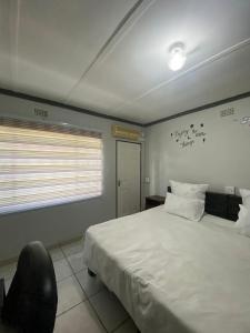 a bedroom with a white bed and a chair at liam travel inn in Nelspruit