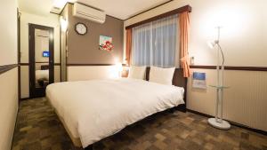 Un dormitorio con una gran cama blanca y una lámpara en Toyoko Inn Osaka Umeda Nakatsu No.2, en Osaka