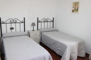 a bedroom with two beds and a dresser with a lamp at Casa Mirasierra in Mota del Cuervo
