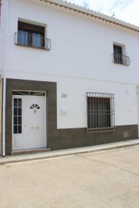 a white building with a white door and two windows at Casa Mirasierra in Mota del Cuervo