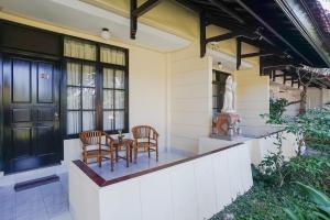 un porche delantero de una casa con 2 sillas y una mesa en Hotel Oranjje, en Denpasar
