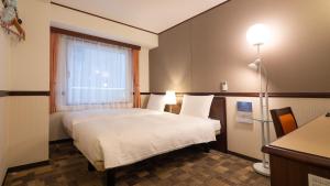 Toyoko Inn Osaka Umeda Nakatsu No.2 في أوساكا: غرفه فندقيه بسرير ونافذه