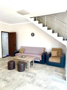a living room with a couch and a table and stairs at Rio cottage apartment in Ureki