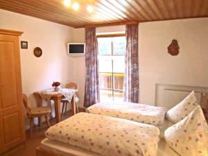 a bedroom with two beds and a table with a window at Bauernhof Ertlhof in Sachrang