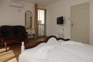 ein Schlafzimmer mit einem Bett, einem Sofa und einem Spiegel in der Unterkunft Стаи за гости RADEA in Dewin
