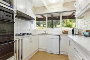 a kitchen with white cabinets and a stove top oven at Gisborne Peak Winery Short Term Stays in Gisborne