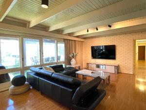 a living room with a black leather couch and a table at Gisborne Peak Winery Short Term Stays in Gisborne