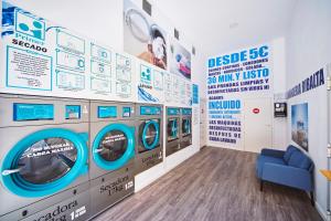 a laundry room with four washing machines and a blue couch at RIBALTA SENSACIONES in Castellón de la Plana