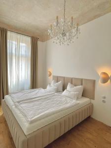 een slaapkamer met een groot wit bed en een kroonluchter bij Apartmá Adina 1905 in Karlsbad