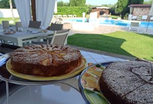 two cakes on plates on a table near a pool at Il Giardino dei Pini in Paestum