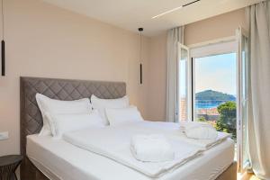 a bedroom with a large white bed with a window at New & Stunning Views in Luxury 5* Divona Apartment in Dubrovnik