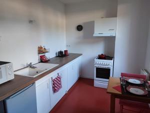 a kitchen with white cabinets and a sink and a stove at Studio avec une cour. in Joigny +8 photos