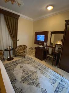 een woonkamer met een televisie en een groot tapijt bij Hayat Redwa Hotel in Yanbu