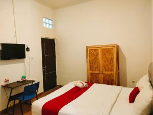 - une chambre avec un lit avec un animal rembourré dans l'établissement RedDoorz At Sukomanunggal Surabaya, à Surabaya