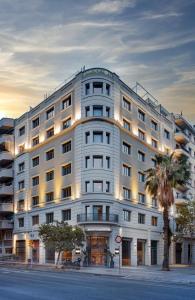 a large white building with a palm tree in front of it at Sercotel Amister Art Hotel Barcelona in Barcelona