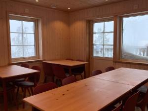 een kamer met houten tafels, stoelen en ramen bij Fjällvidden - lyxig fjällstuga i Idre in Idrefjäll