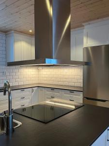 a kitchen with white cabinets and a stainless steel refrigerator at Fjällvidden - lyxig fjällstuga i Idre in Idre Fjäll