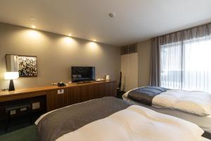 a hotel room with two beds and a flat screen tv at Oyado Kyoto Shinmachi in Kyoto