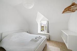 a white bedroom with a bed and a window at - Duin 63 - Ruim 8 pers duplex app met terras in Koksijde