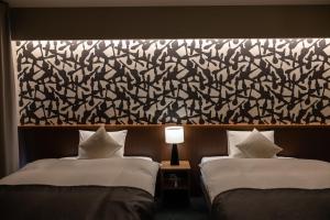 two beds in a hotel room with a large wall at Oyado Kyoto Shinmachi in Kyoto